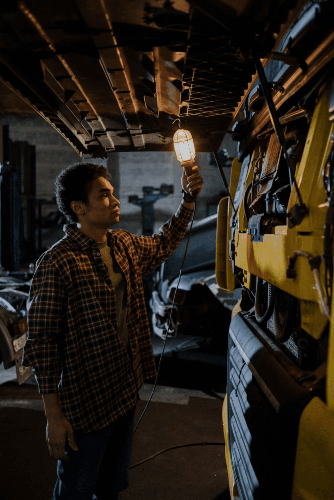 A mechanic holds up a light bulb to a truck’s exteriors during an examination.