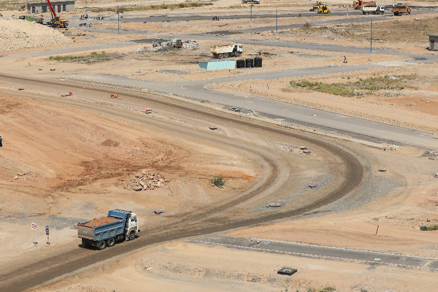 A dump truck travels along a dirt road in a barren area