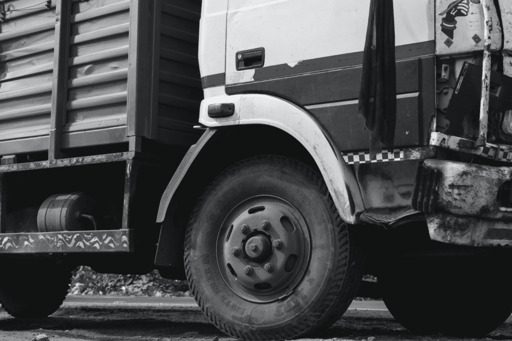 A grayscale close-up photo of a truck wheel, highlighting its rugged texture and industrial design.