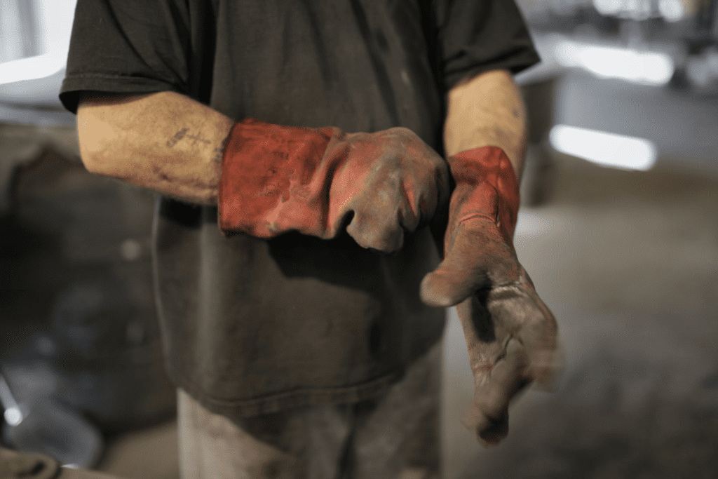 Mid-section of a workshop mechanic as he pulls on heavy-duty gloves