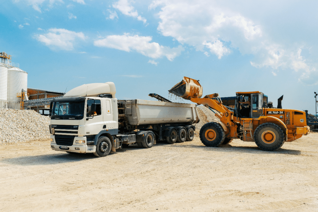 A brown loader filling a dump truck