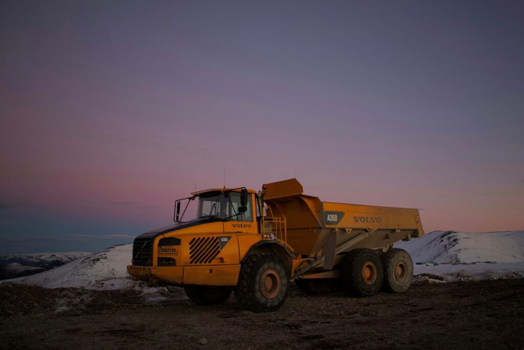 A yellow dump truck is parked on a rocky terrain.