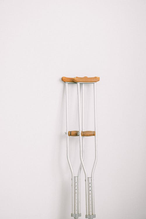A pair of crutches leaning against a white wall, symbolizing injury recovery.