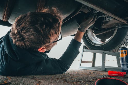 Mechanic working underneath a raised dump truck during a repair