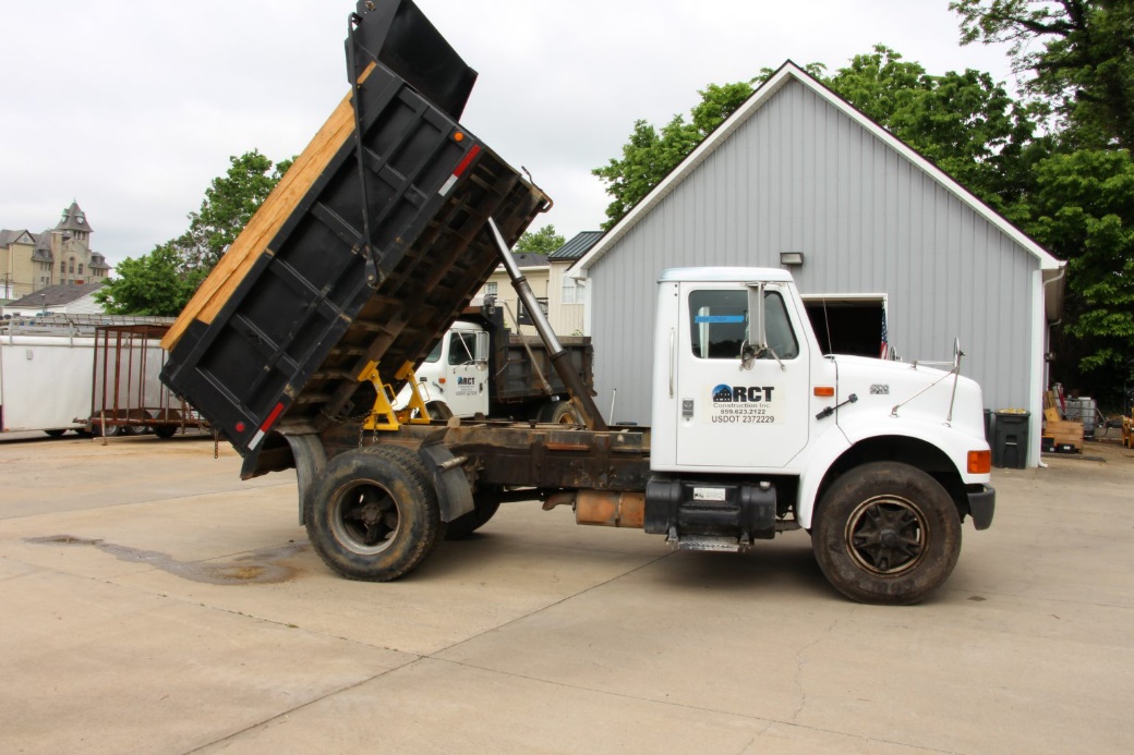 A BedLock system is safely installed on a dump truck during maintenance in a repair shop