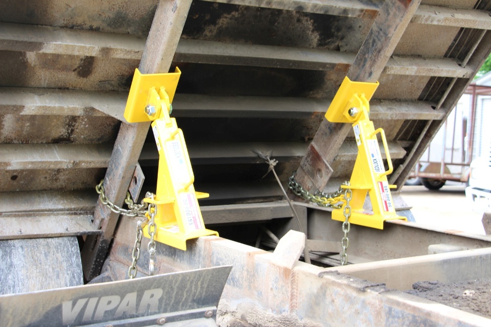 A BedLock truck bed lock fully installed on a dump truck to prevent accidental lowering during maintenance