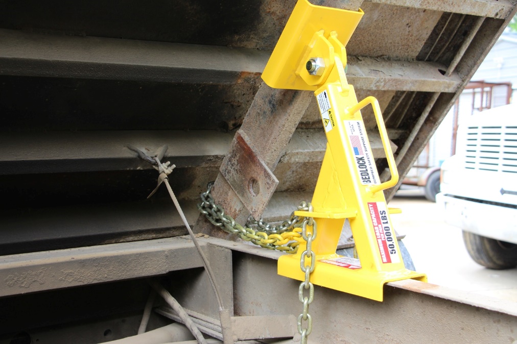 A truck bed lock properly installed on a dump truck in a maintenance facility