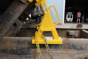 Close-up view of a BedLock safety device installed beneath a raised dump truck bed