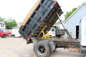 Dump truck with two BedLock safety devices securing the raised bed