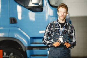 Mechanic in a truck repair facility holding two tools, ready for servicing tasks