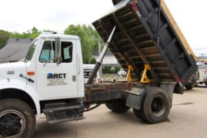 A second dump truck with its bed elevated and secured using two BedLock devices