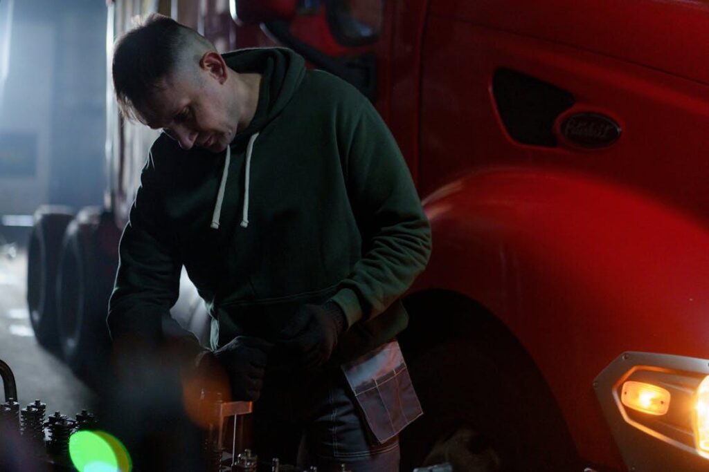 A technician in a hoodie inside a truck maintenance facility