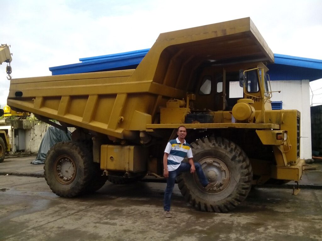 Technician standing beside a dump truck at a maintenance facility for repairs