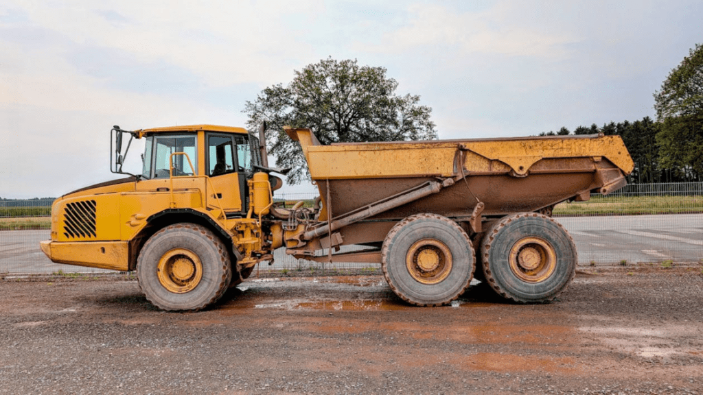 Dump truck unloading construction materials at an active job site under clear daylight conditions.
