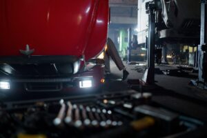 Technician repairing a truck inside a workshop, performing maintenance tasks on a heavy-duty vehicle.