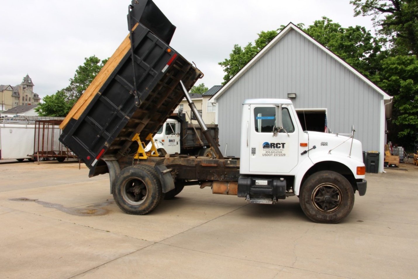 A dump truck at a repair facility with two BedLock truck bed locks installed on a raised bed for maximum safety.