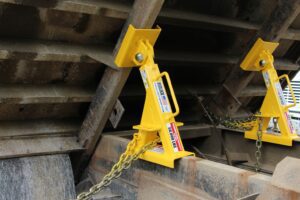 Close-up of truck bed locks installed under a raised dump truck bed for safety support