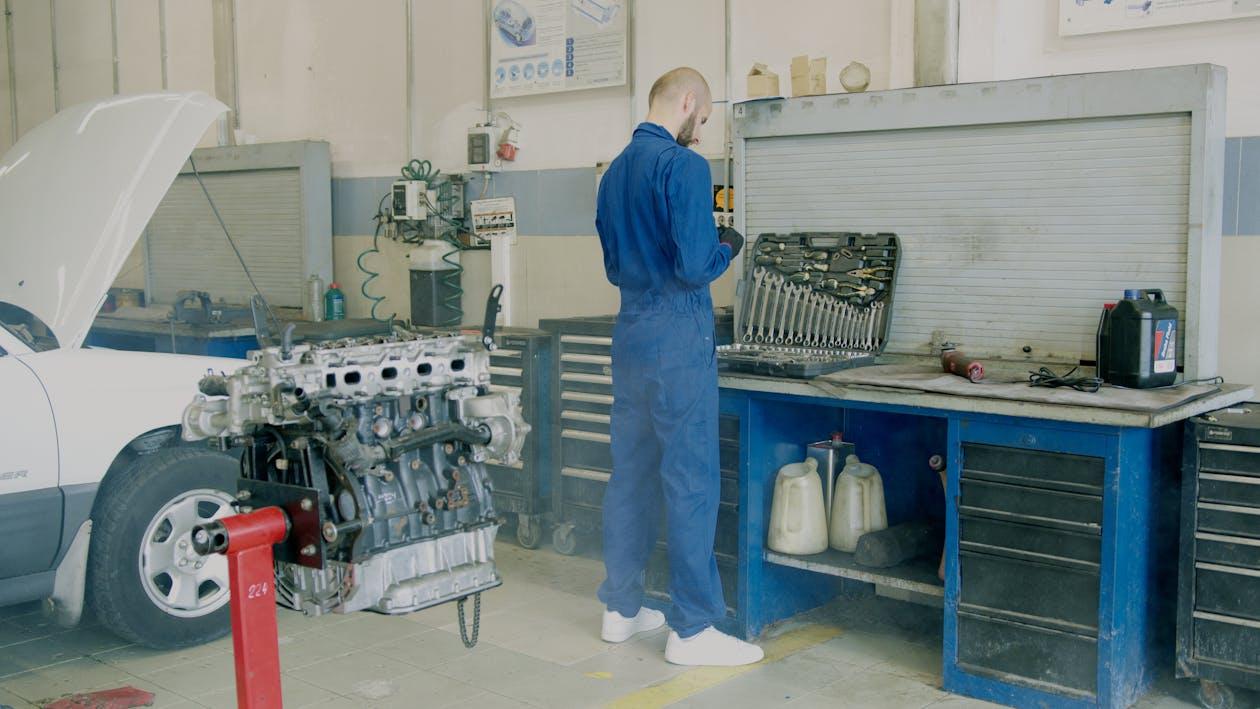 Technician working on a vehicle inside a repair shop, following maintenance and safety procedures