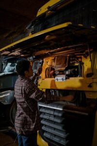 Technician inspecting internal parts of a yellow truck during maintenance