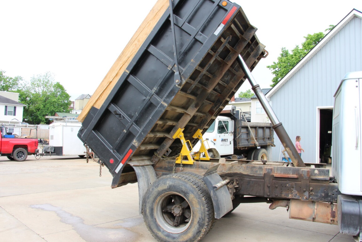 Two bed locks installed under a raised dump truck bed during maintenance