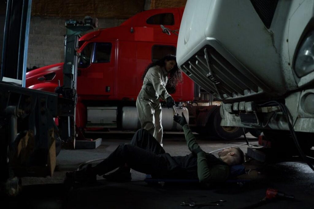 Technician working beneath a raised truck