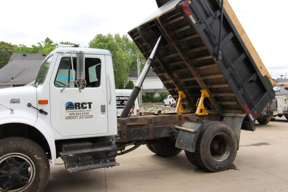 A dump bed safety support device holding a raised truck bed in place during service.