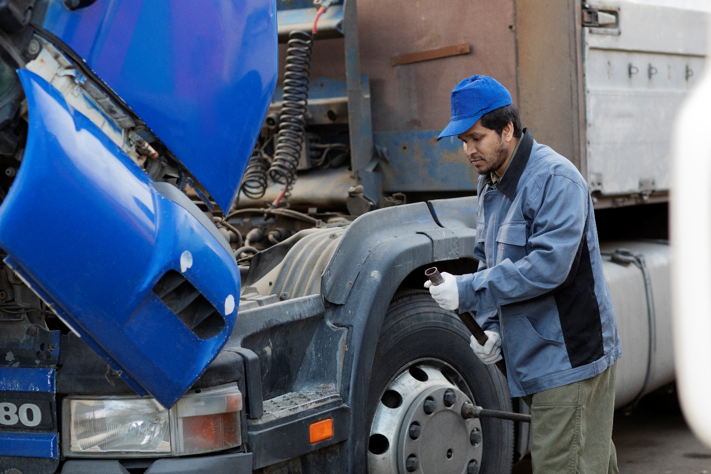 Mechanic working on a truck engine, checking equipment fit in a repair workshop.